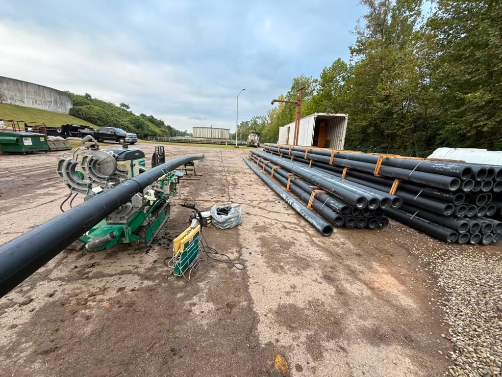 HDPE pipe staged along a road with a fusion machine